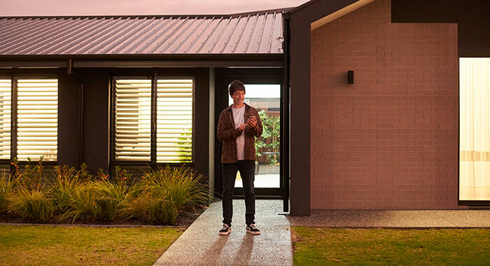 Man standing in front of house using phone.